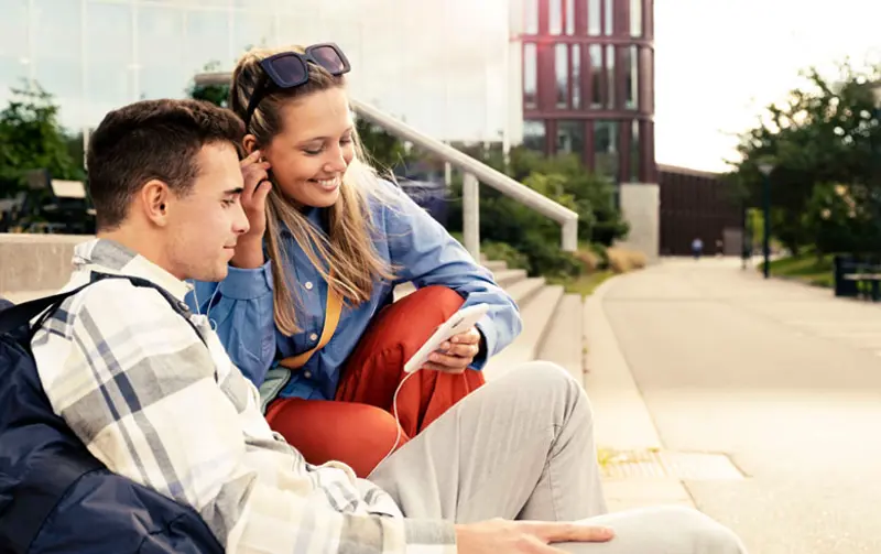 Två ungdomar som tittar på en mobiltelefon