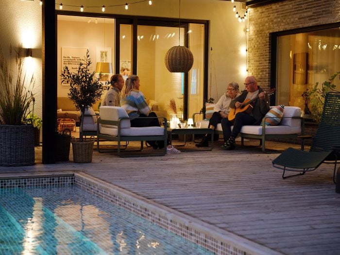 familj i ett hus vid en pool med en man som spelar gitarr