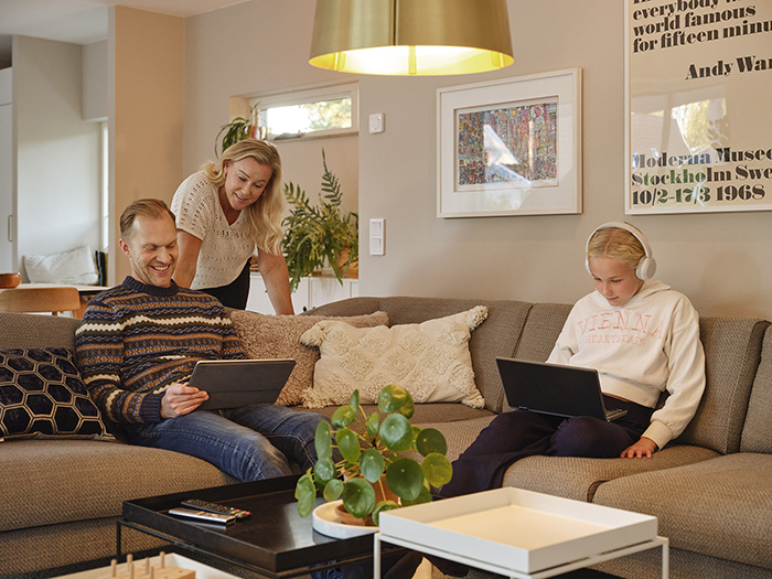 familj sitter i soffan och tittar i sina datorer