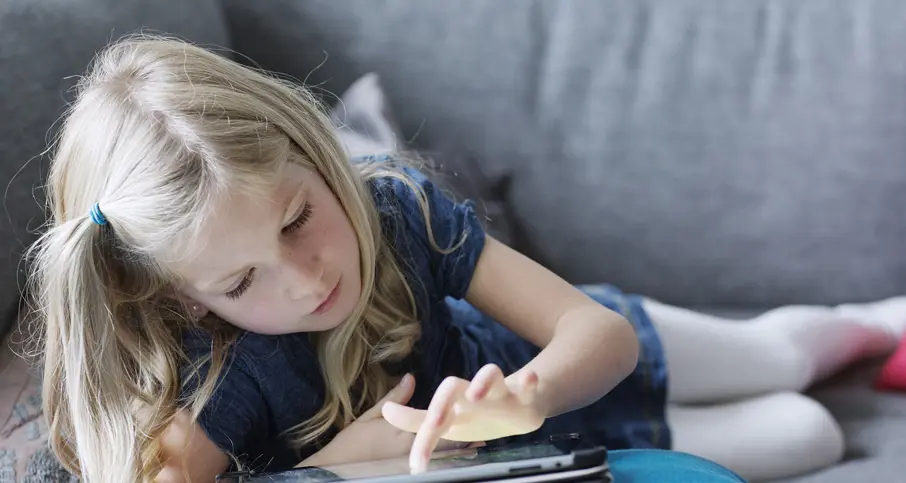 flicka ligger på soffan med en surfplatta i handen